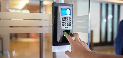 Someone scanning their finger on a security pad to enter a glass office