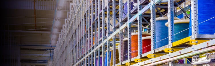 Wire reel holders varying in colors being stored on shelves in a warehouse