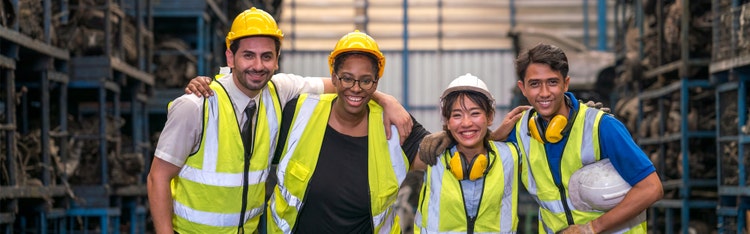 Four warehouse associates smiling for a picture in their uniform
