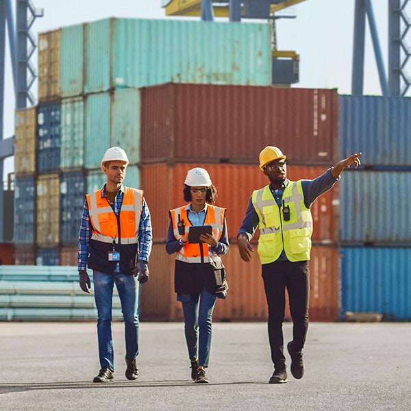 Three co-workers in uniform walking down the cargo yard